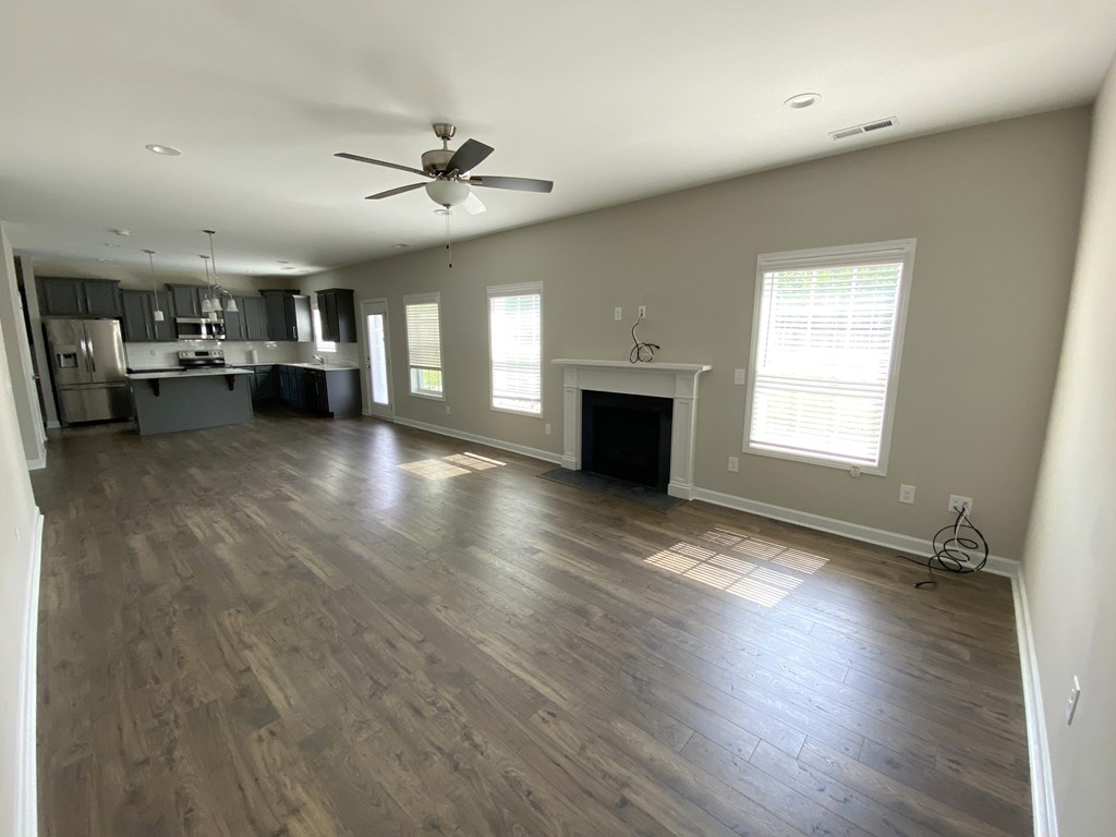 A spacious living room with wood flooring and a ceiling fan.