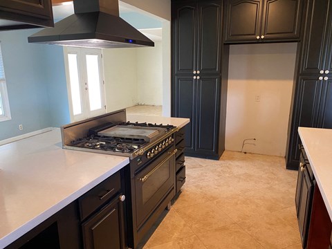 a kitchen with a stove and a counter top and black cabinets