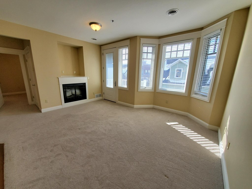 an empty living room with a fireplace and large windows