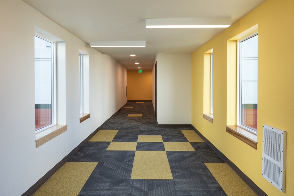 a hallway with windows and a carpeted floor and yellow walls