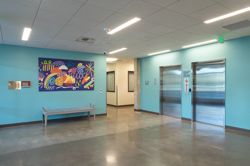 a hallway with two doors and a painting on the wall and a bench