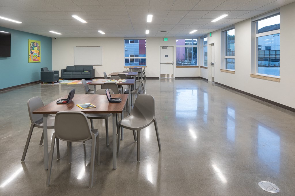 a common area with tables and chairs and a projection screen on the wall