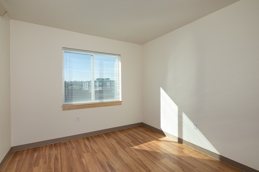 an empty room with wooden floors and a window