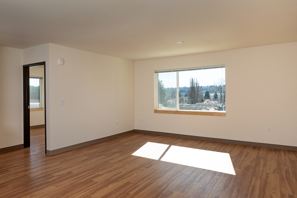 an empty living room with wood floors and a window