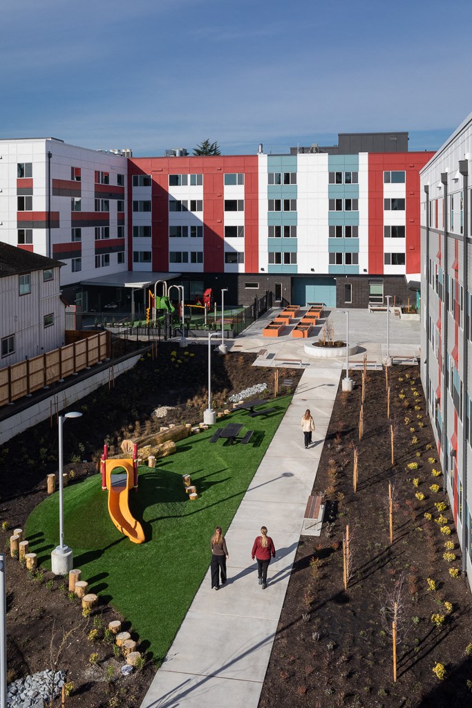 people walking through a park in front of buildings