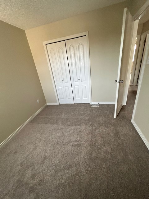 a bedroom with a carpeted floor and a closet