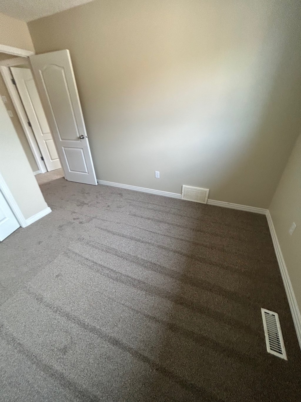 a living room with carpet and a door into a hallway