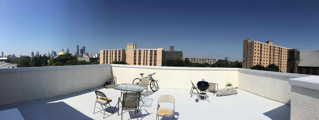 a rooftop patio with a table and chairs and a bike on it