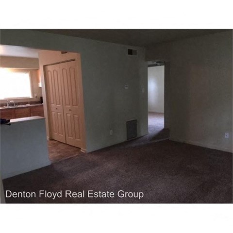 A room with a carpeted floor and a door leading to another room.
