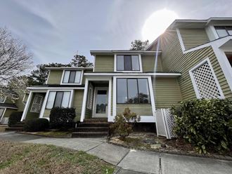 a yellow house with white windows and a sidewalk