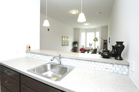 A kitchen with a white counter top and a stainless steel sink.