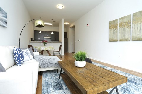 A white couch with blue pillows sits in a living room with a wooden coffee table.