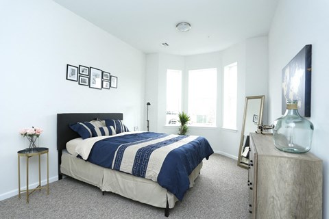 A bedroom with a bed, nightstand, and a window.