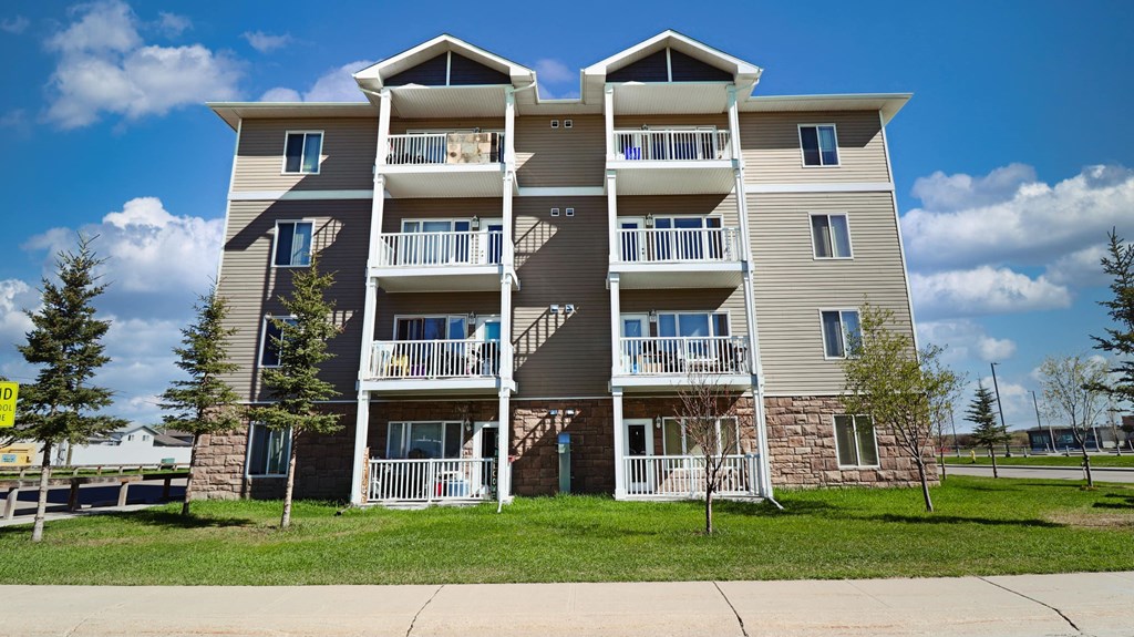 an exterior view of an apartment building with balconies and grass