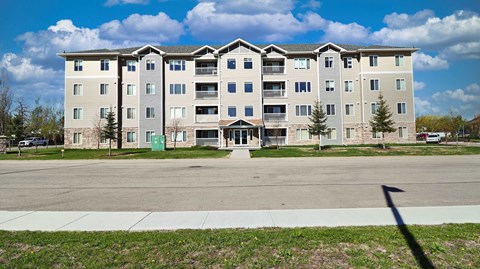A large apartment building with a green door and a white fence.