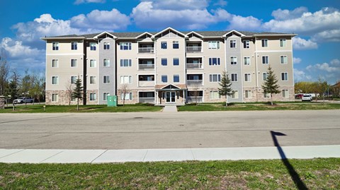 A large apartment building with a green door and a white fence.