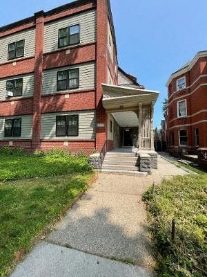 a large brick building with a porch and a sidewalk