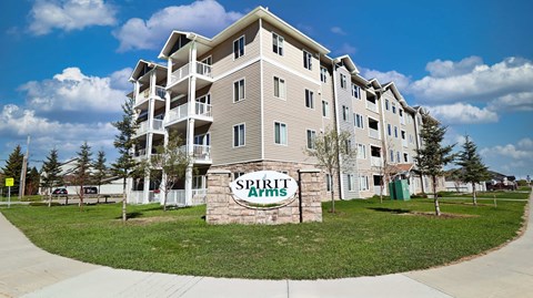 A large brick building with the words "Spirit Apartments" on a stone pillar in front.
