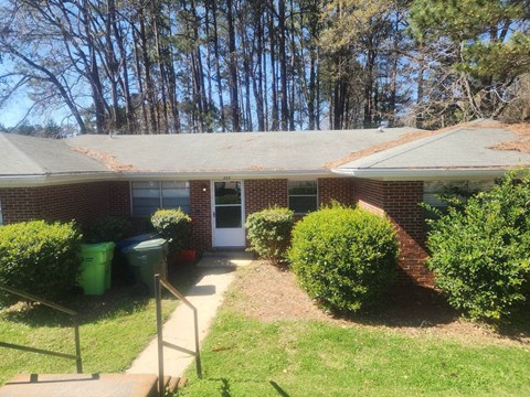 A house with a green lawn and a red brick wall.