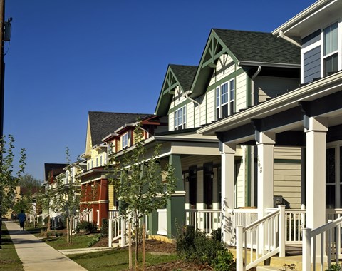 A row of houses with green roofs and white porches.