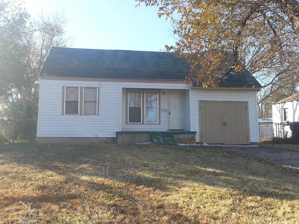 a small white house with a yard and a garage