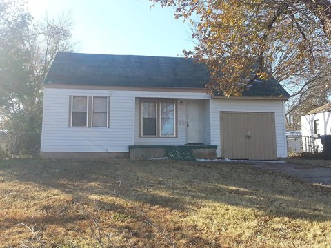 a small white house with a yard and a garage