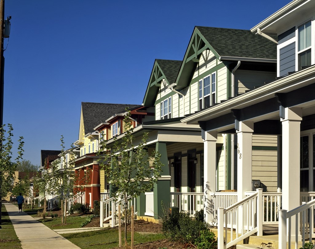 a row of green and white houses on the side of a sidewalk