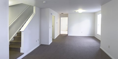 an empty living room with a staircase and white walls