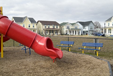 a red slide on a playground in front of houses
