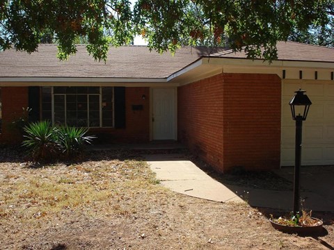 a sidewalk in front of a brick house