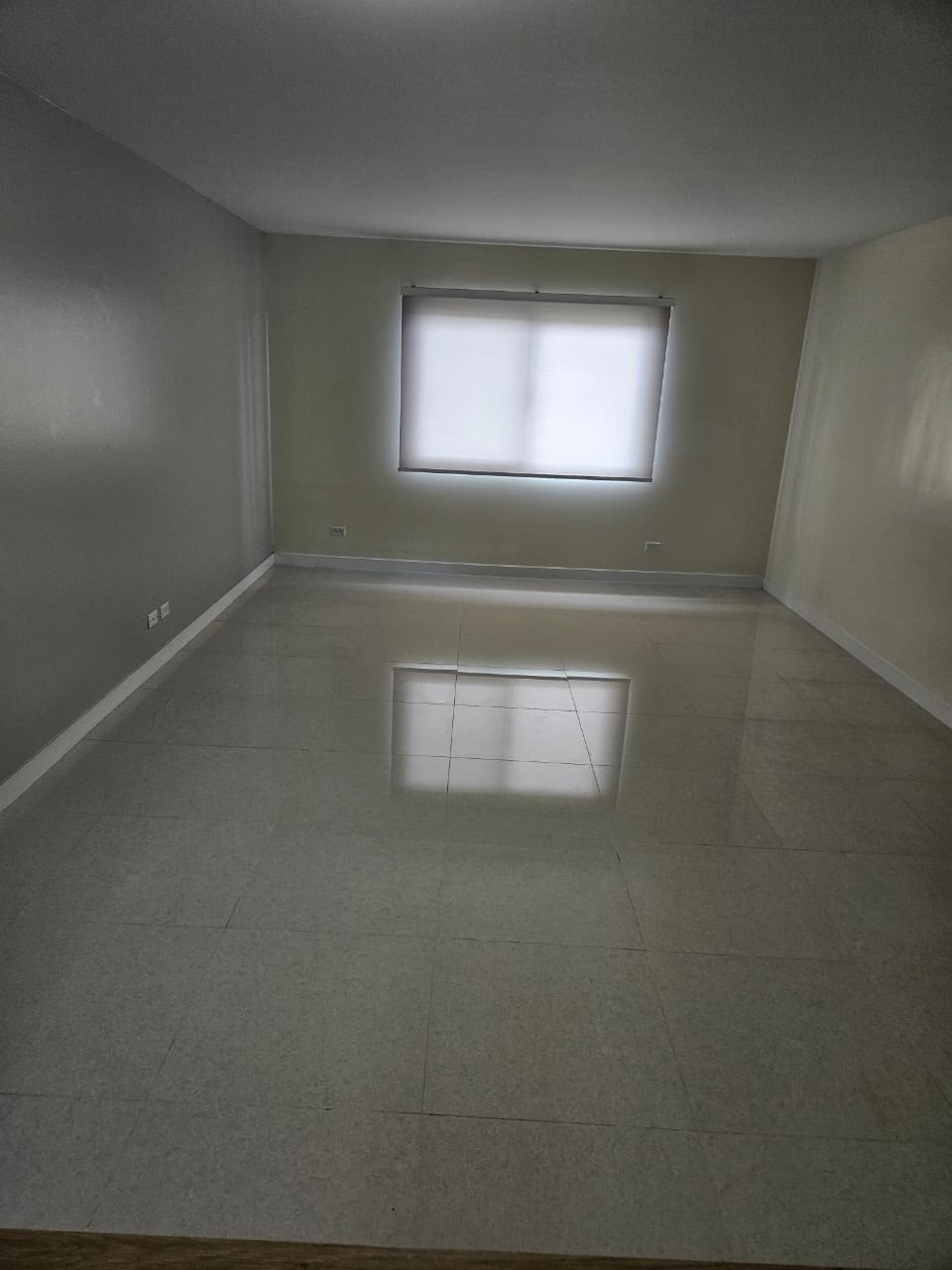 A room with a window and a tiled floor.