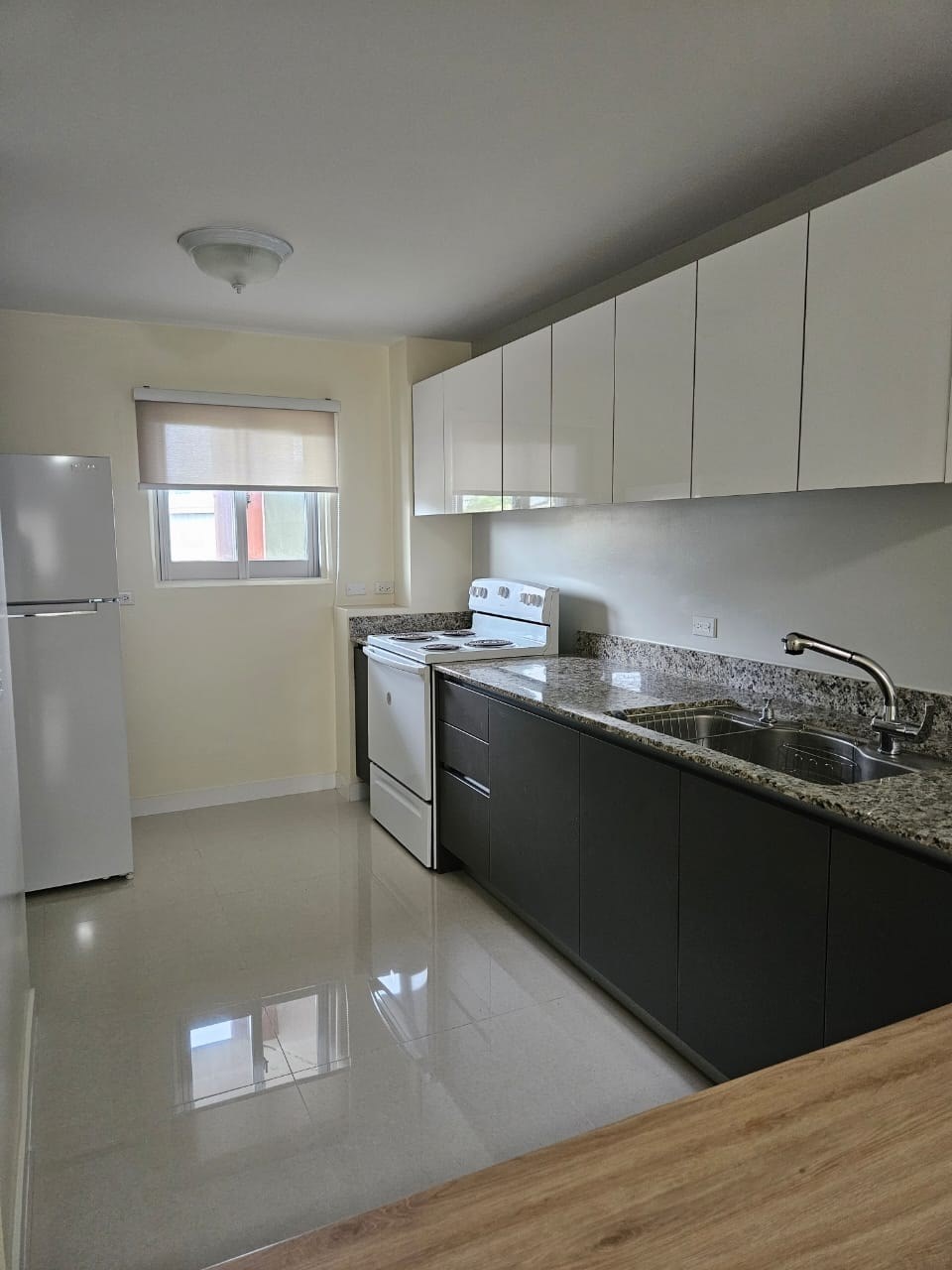 A kitchen with a white fridge, black cabinets, and a granite countertop.