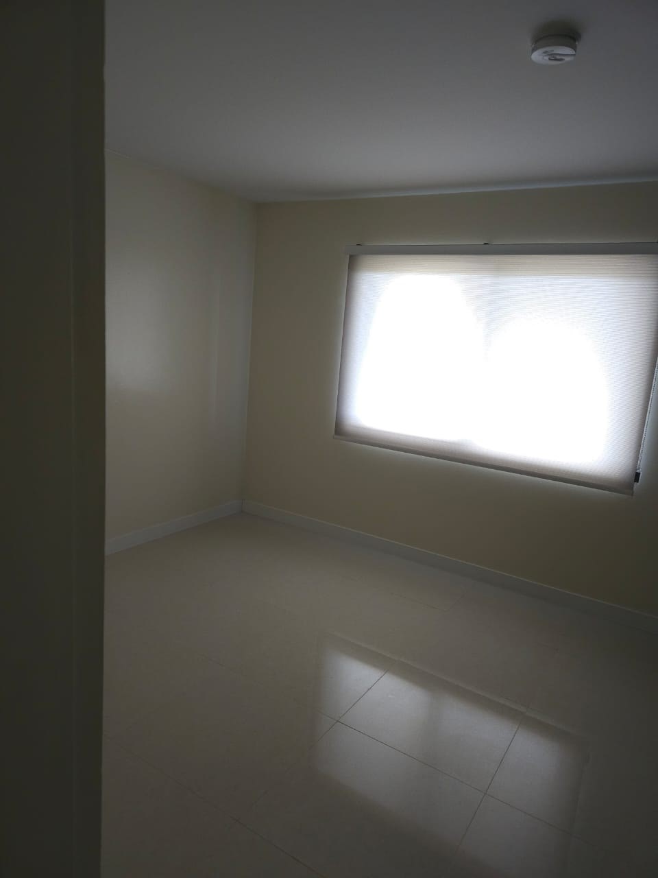 A room with a window and a tiled floor.