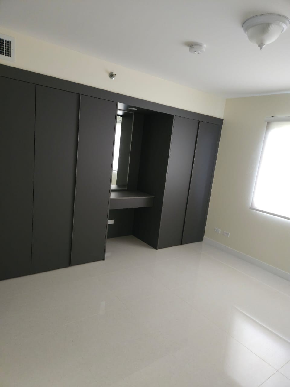 A large empty room with a wardrobe and a mirror.