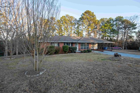 A house with a red roof and a tree with no leaves in front of it.