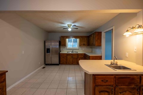 A kitchen with a refrigerator, sink, and wooden cabinets.