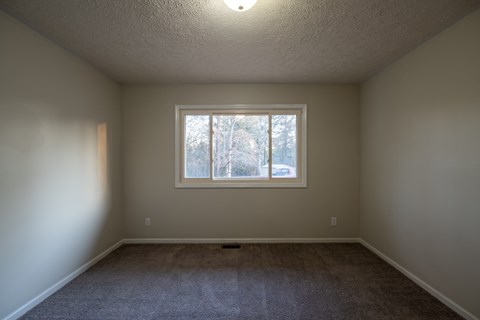 A room with a window and carpeted floor.