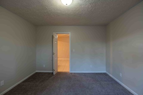 A room with a carpeted floor and a doorway leading to another room.