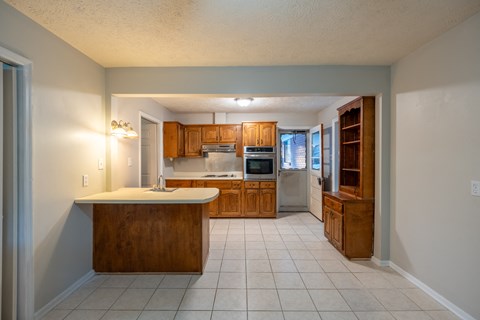 A kitchen with a wooden island and white tile flooring.