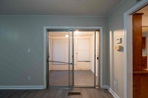 A room with a white door and a brown floor.