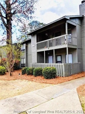 A two-story building with a balcony and a fence in front.