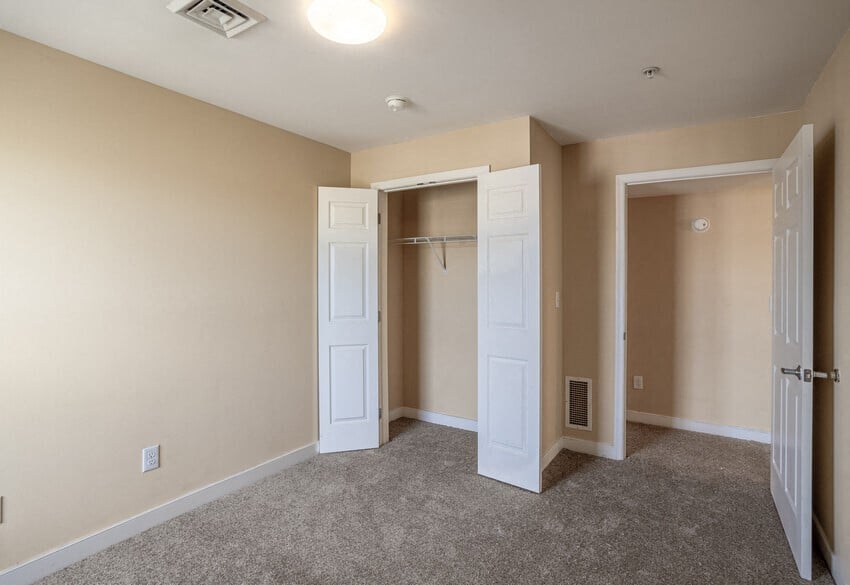 an empty room with two doors and a closet