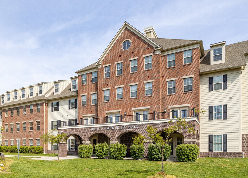 the front of a brick building with a green lawn