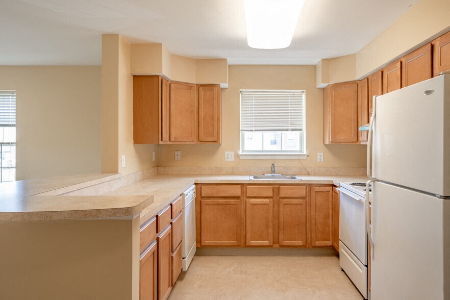 an empty kitchen with wooden cabinets and a refrigerator