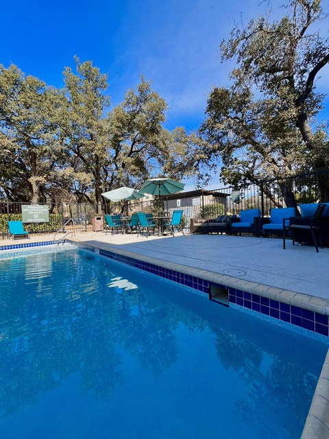 a swimming pool with chairs and umbrellas next to a resort style pool