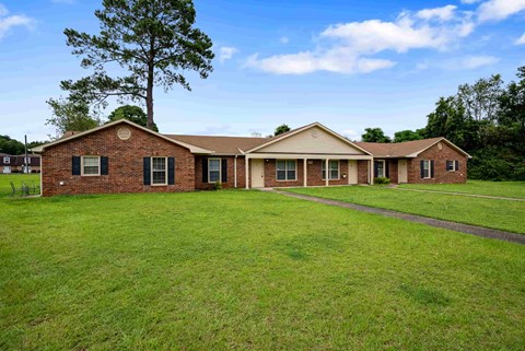 A brick house with a green lawn in front.