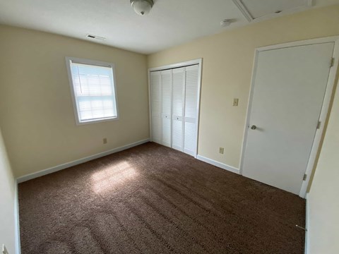 A room with brown carpet and a window.