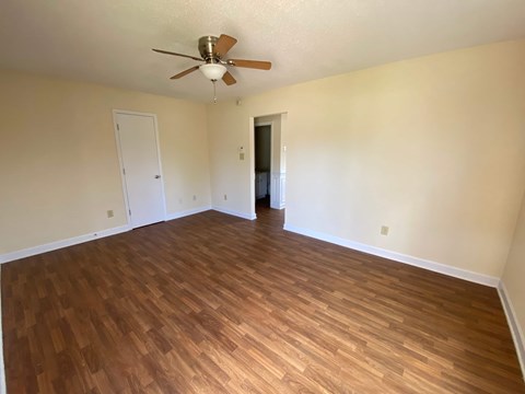 A room with a ceiling fan and wooden flooring.