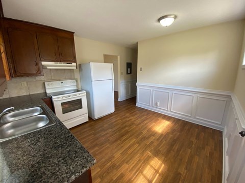 A kitchen with wooden cabinets and a white fridge.