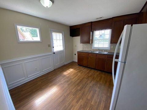 A kitchen with wooden floors and white appliances.